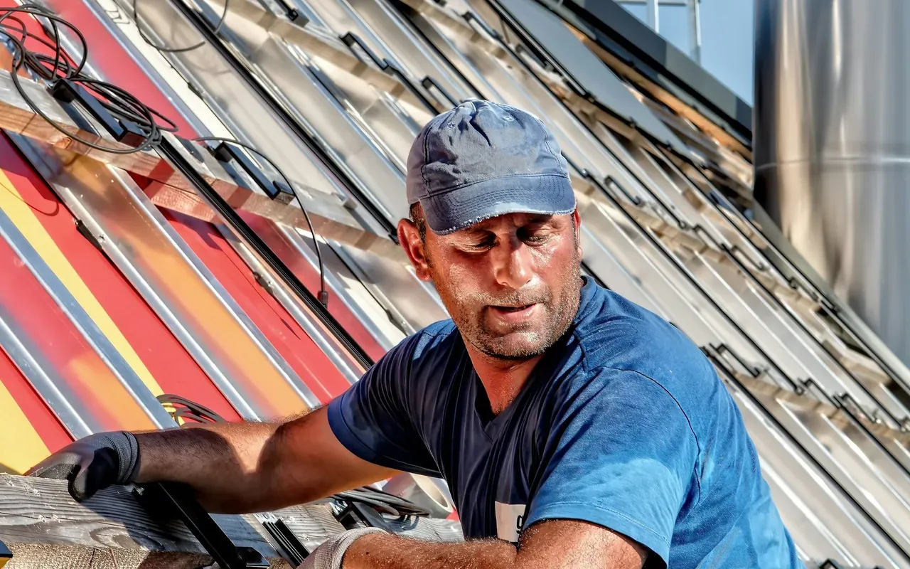 Technician working on a sloped metal roof with solar mounting rails