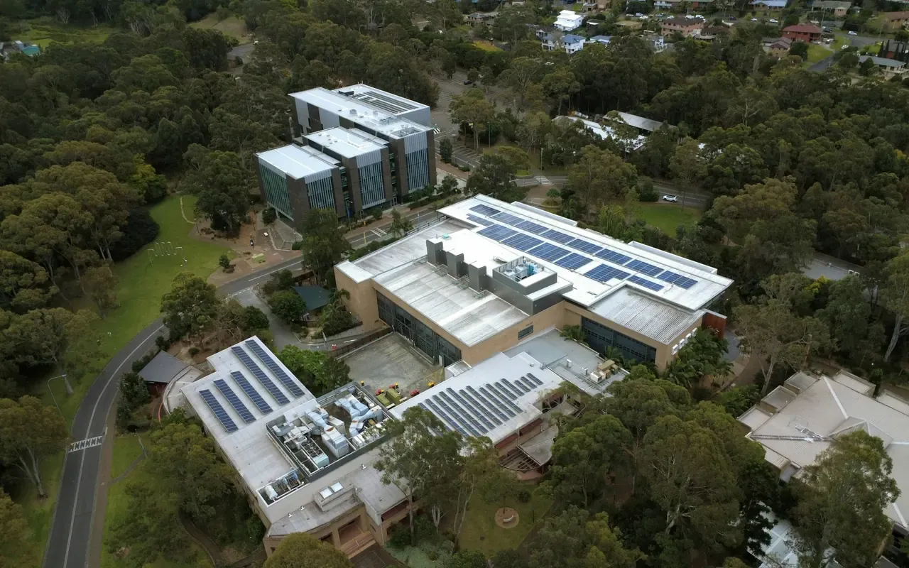 Aerial view of a campus with rooftop solar among dense green trees